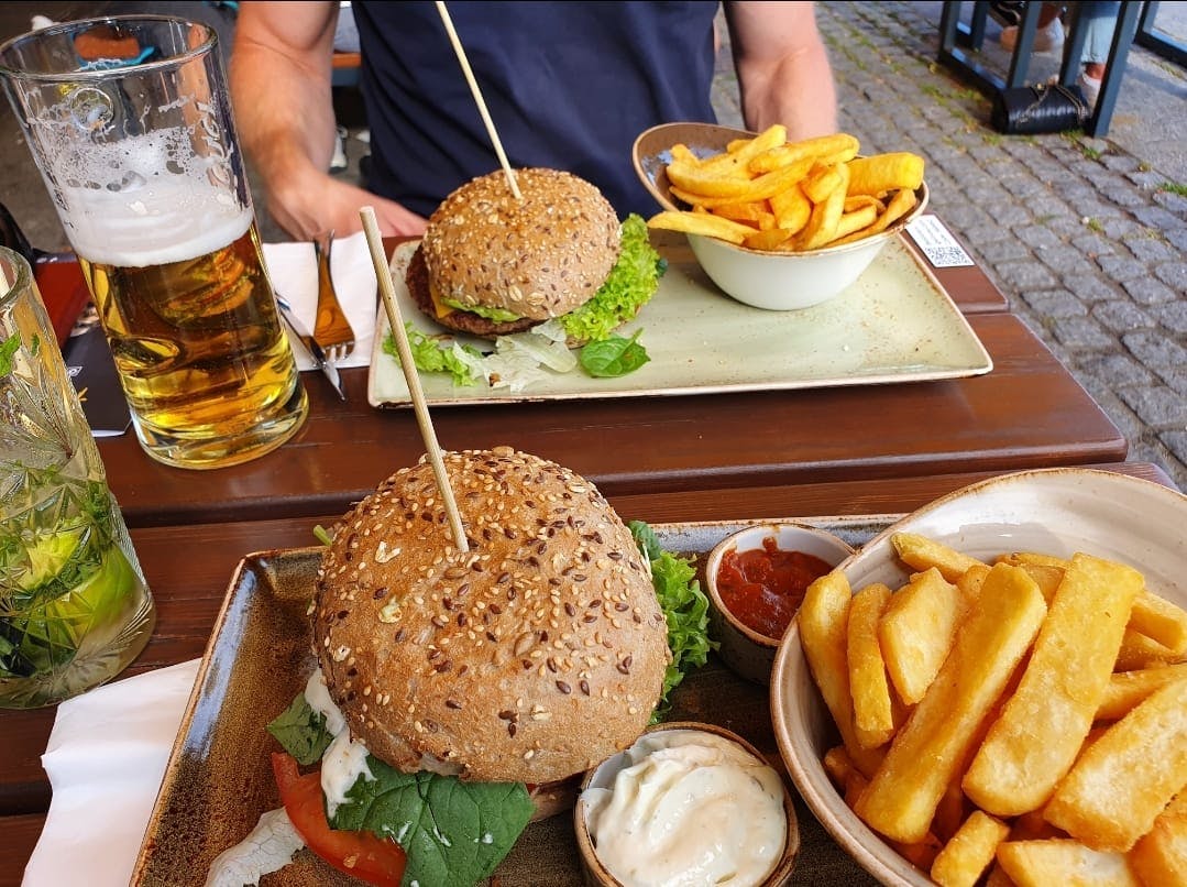 Burgers, drinks on a table between friends.